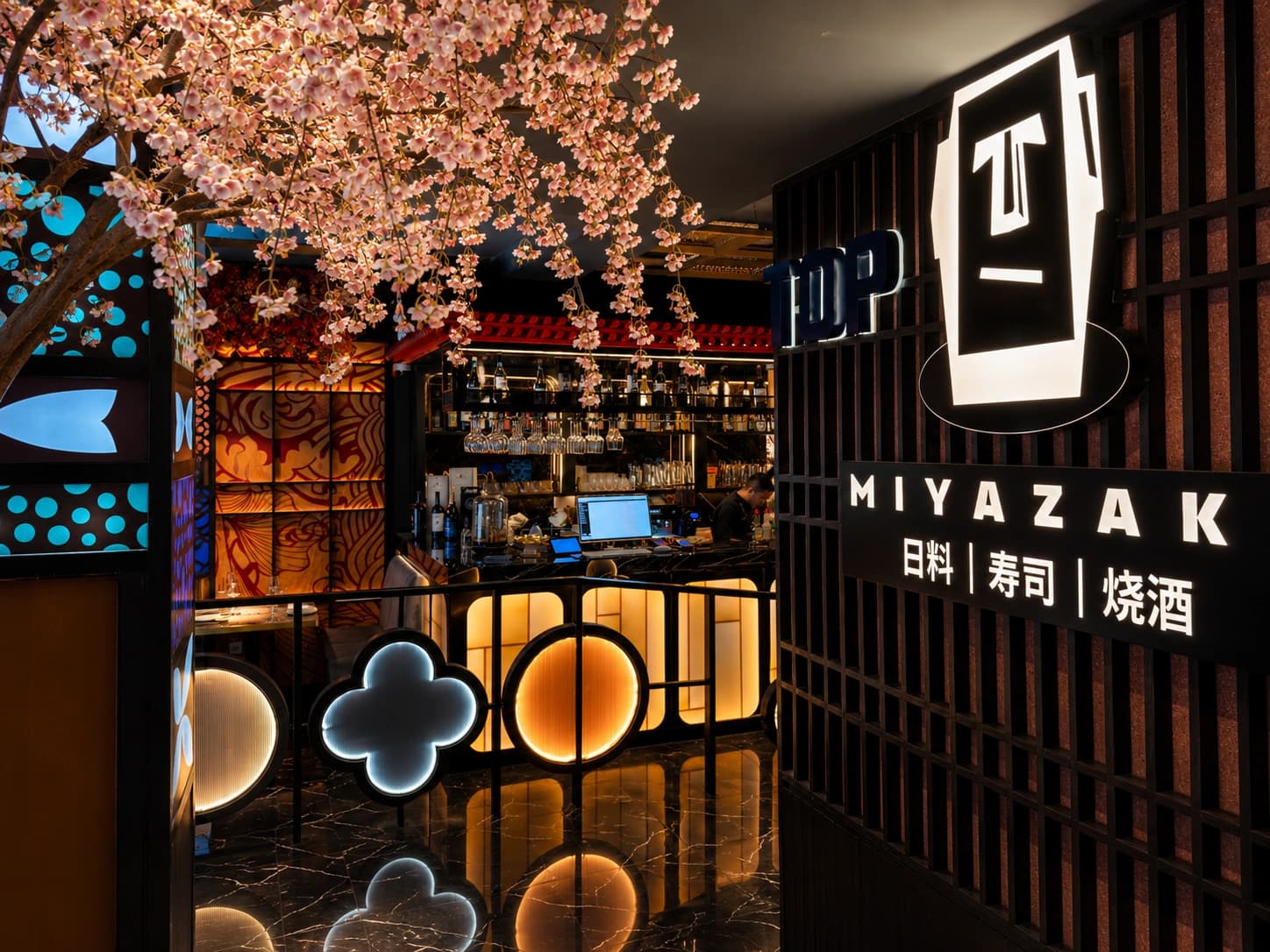 Entrada do Miyazaki com cerejeira iluminada e sinal do restaurante